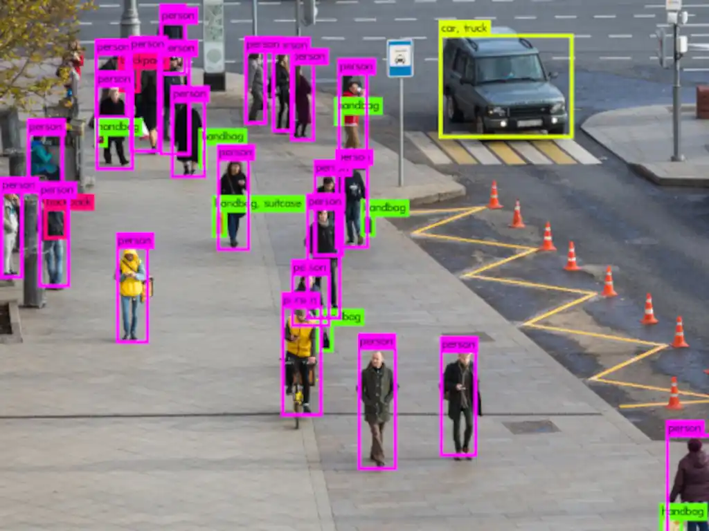 Computer vision tracks pedestrians and a black SUV on a tiled urban street.