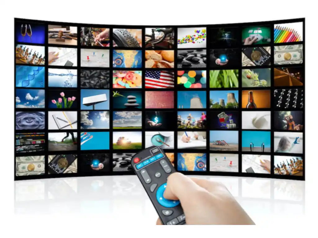 Hand with remote control and 4x6 grid of 24 images on a curved TV screen.